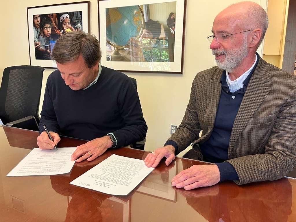 André Sendin e Raul Reis sentados à mesa a assinar documentos de parceria académica.