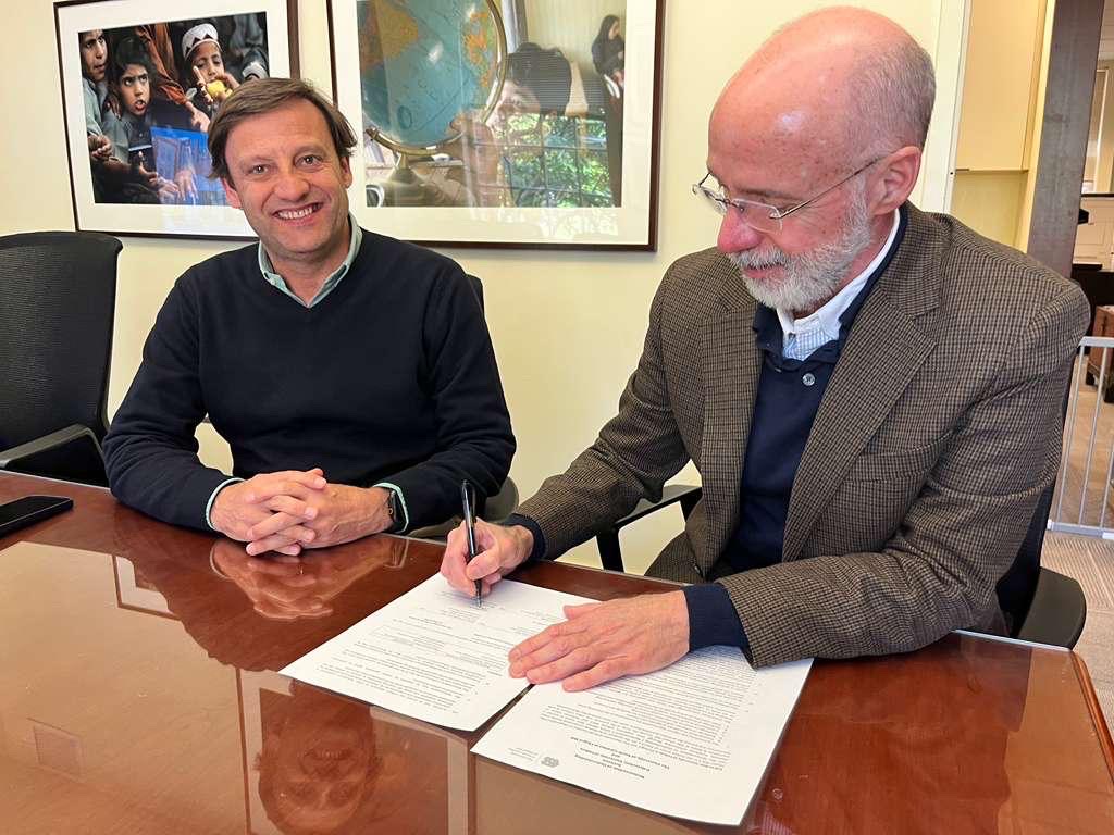 André Sendin e Raul Reis sentados à mesa a assinar documentos de parceria académica.