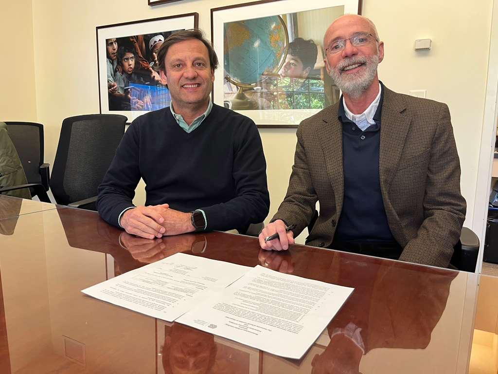 André Sendin e Raul Reis sentados à mesa a assinar documentos de parceria académica.